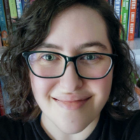 Rikki Bleiweiss headshot smiling in front of a bookshelf