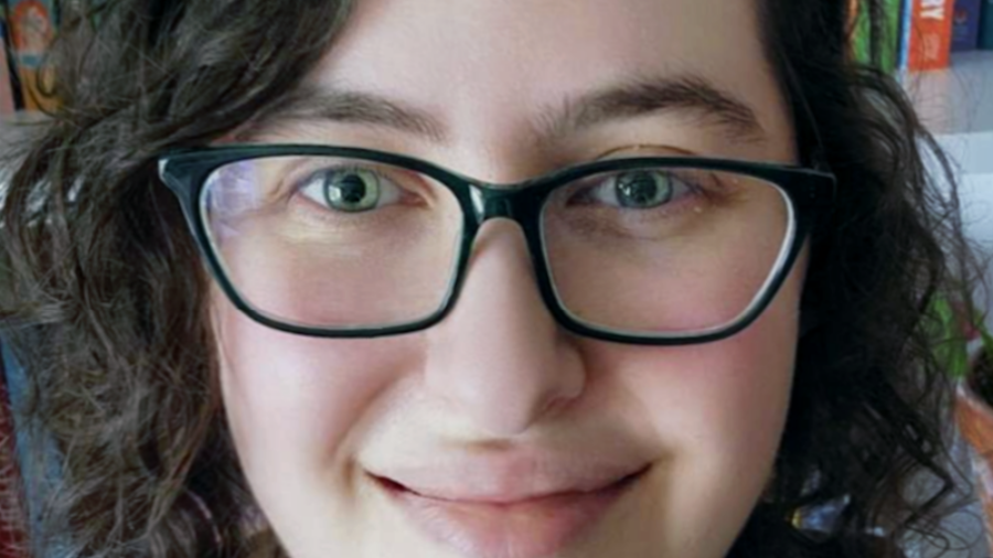 Rikki Bleiweiss headshot smiling in front of a bookshelf