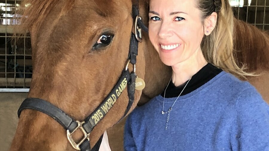 Sabrina Mansfield smiling with a horse next to her