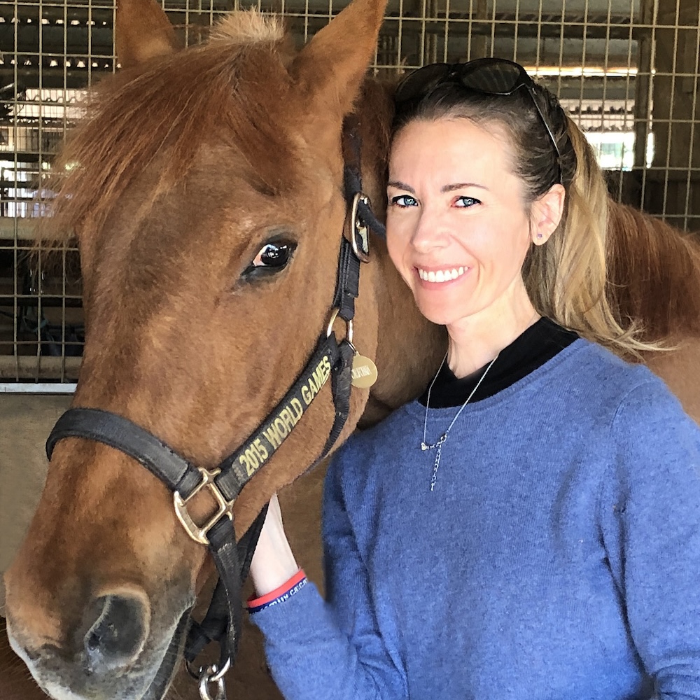 Sabrina Mansfield smiling with a horse next to her