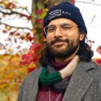 Saleem Nasir Gondal smiling headshot wearing a hat in front of a tree in the fall