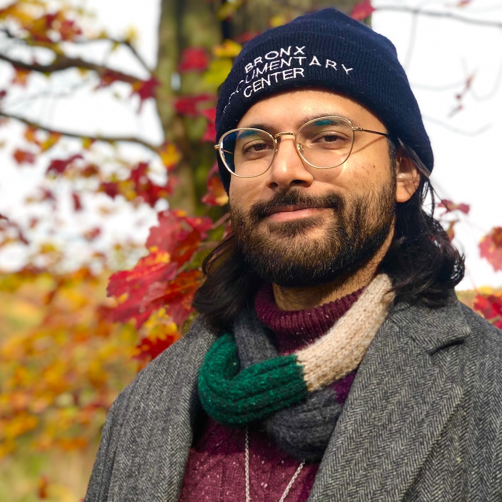 Saleem Nasir Gondal smiling headshot wearing a hat in front of a tree in the fall