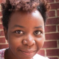 Sandrene Mathews smiling headshot in front of a brick wall