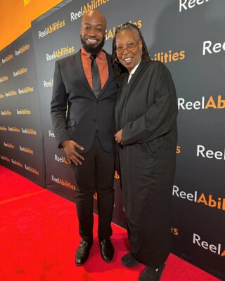 Steven McCoy and Whoopi Goldberg standing on the red carpet with a ReelAbilities step and repeat behind them