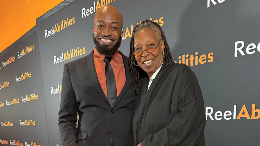 Steven McCoy and Whoopi Goldberg standing on the red carpet with a ReelAbilities step and repeat behind them