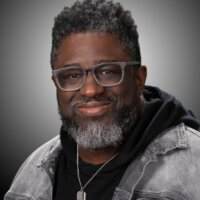 Dr. Lamar Hardwick headshot wearing a gray jacket and glasses