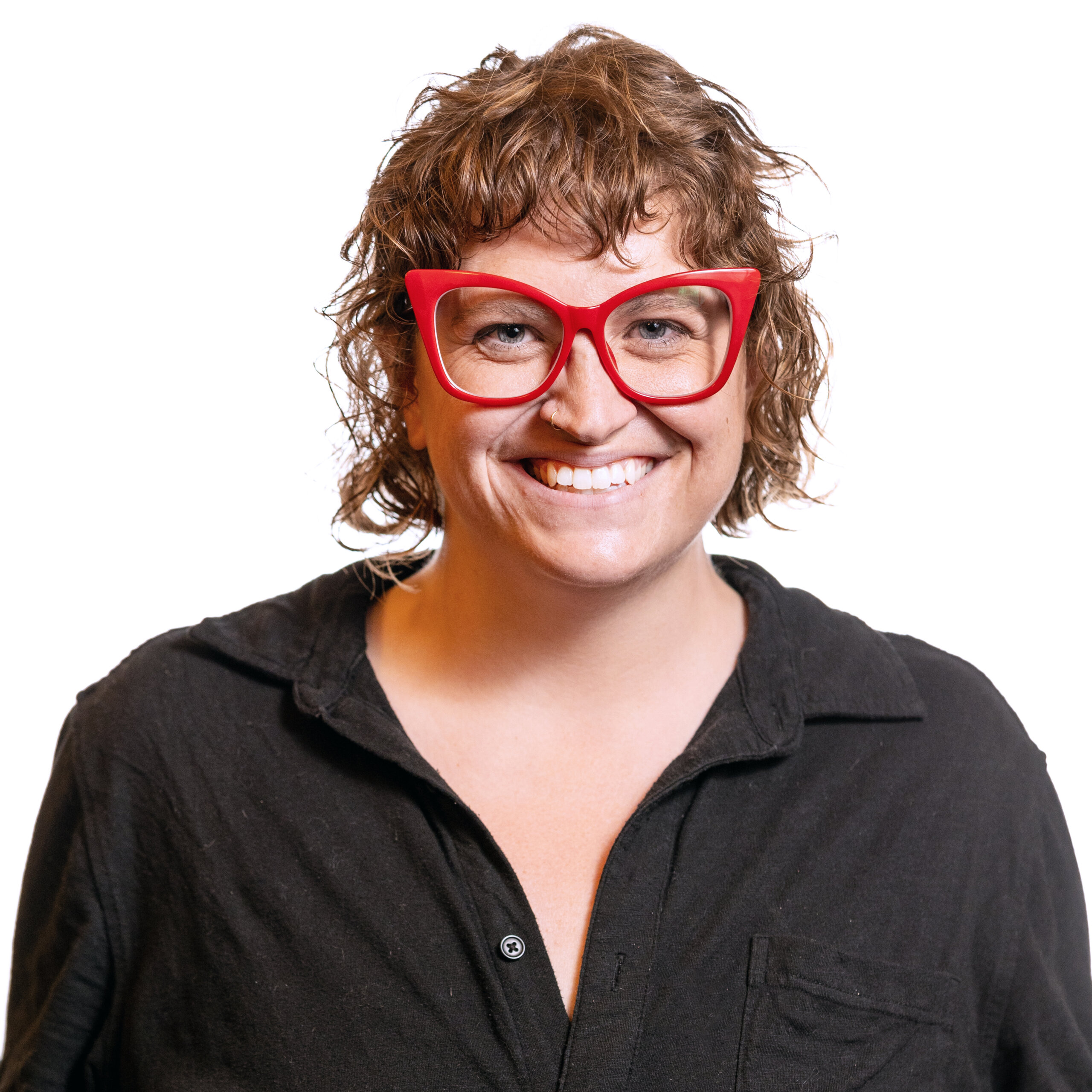 Ally Mills smiling headshot wearing a black button down shirt and big red glasses