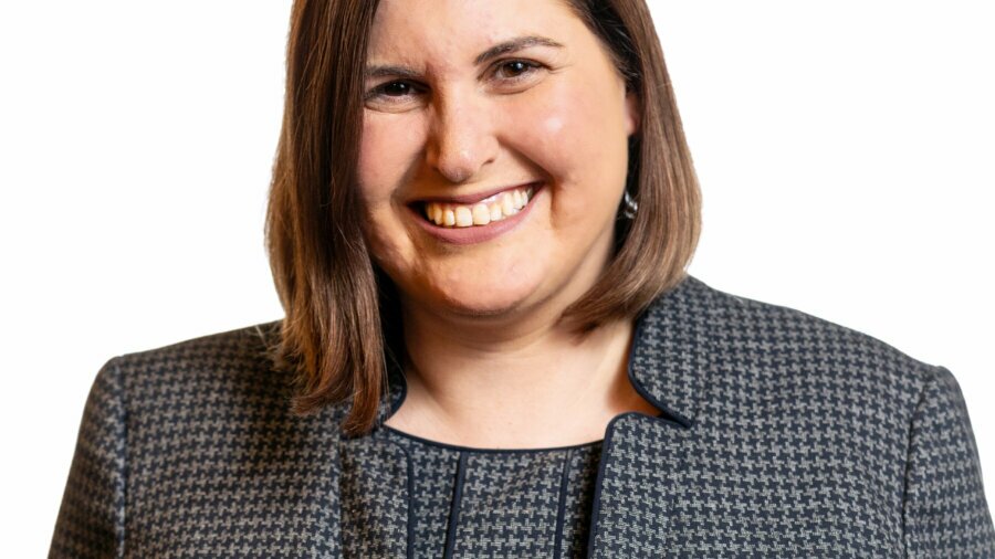 Lauren Appelbaum smiling headshot wearing a black and grey patterned blazer