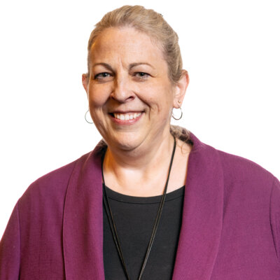 Tonya Koslo smiling headshot wearing a purple jacket