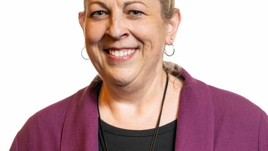 Tonya Koslo smiling headshot wearing a purple jacket
