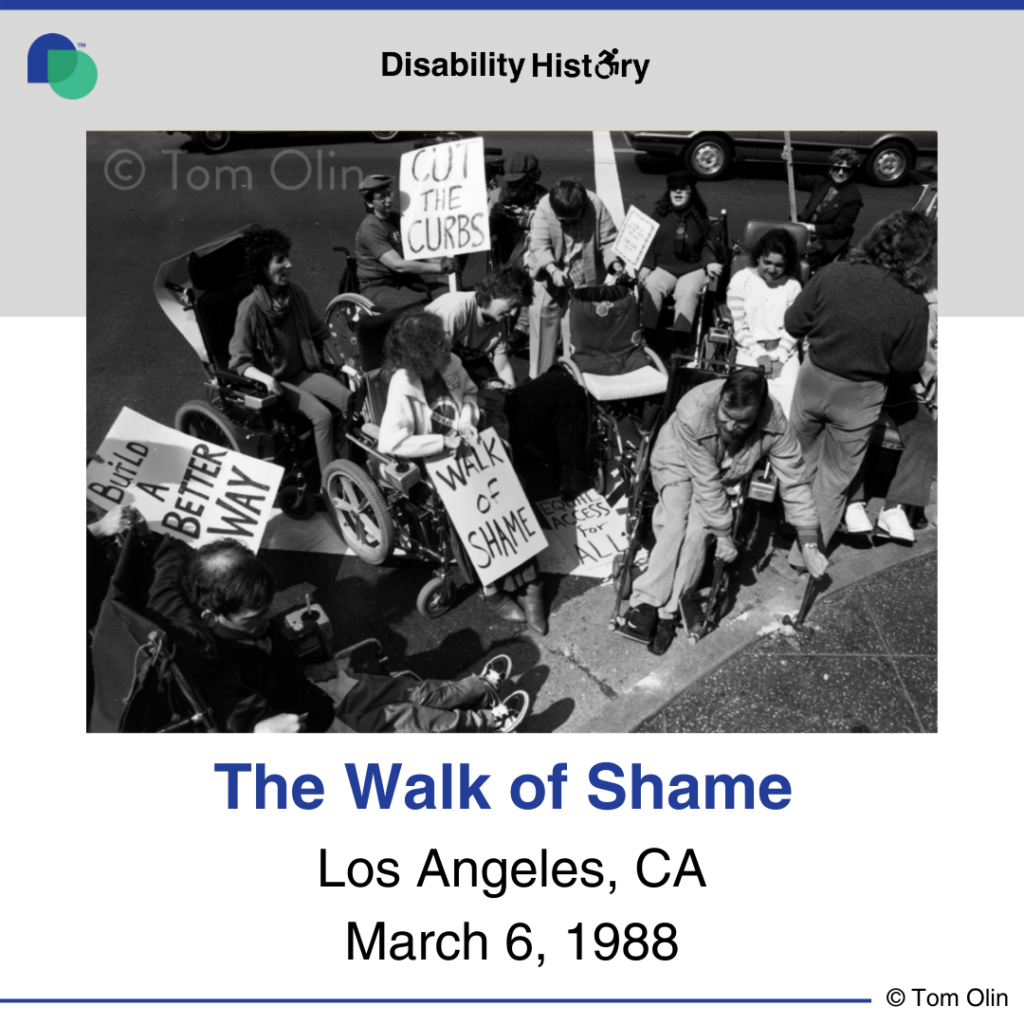 Black and white photo of crowd of protesters in wheelchairs on the road near a curb. One of the protesters is breaking up the curb with a hammer. Three protesters hold signs that say, “Build a better way,” “Walk of shame,” and, “Cut the curbs.” Text: Walk of Shame. Los Angeles, CA. March 6, 1988. Source: Tom Olin.