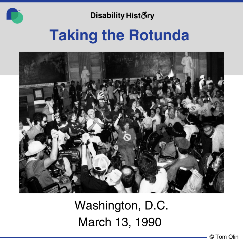 Black and white photo of a crowd of protesters, many in wheelchairs, protesting in the Capitol Rotunda with their fists in the air. Text: Taking the Rotunda. Washington, D.C. March 13, 1990. Source: Tom Olin.