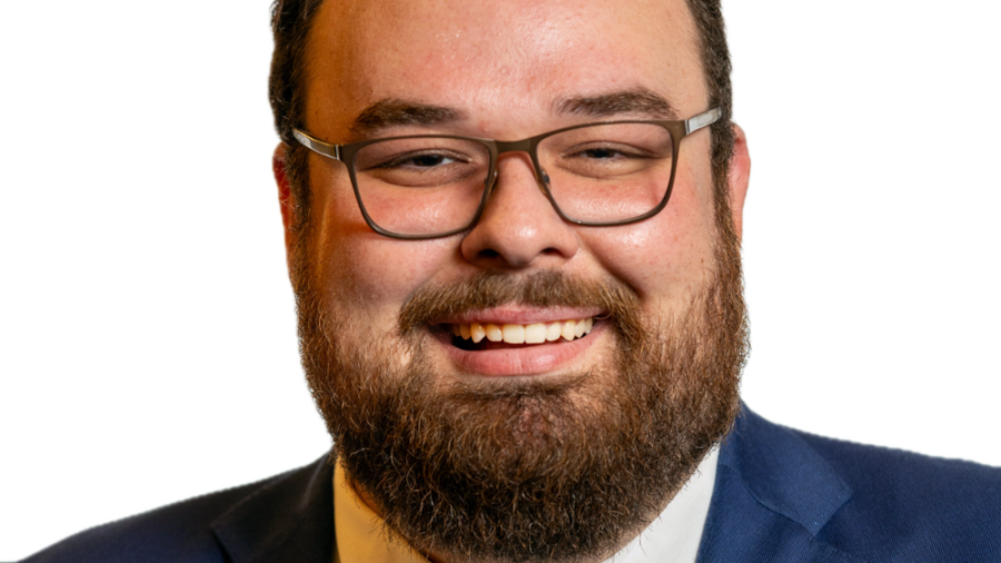 Ben Bond smiling headshot wearing a navy blue blazer, a white dress shirt, and a black tie