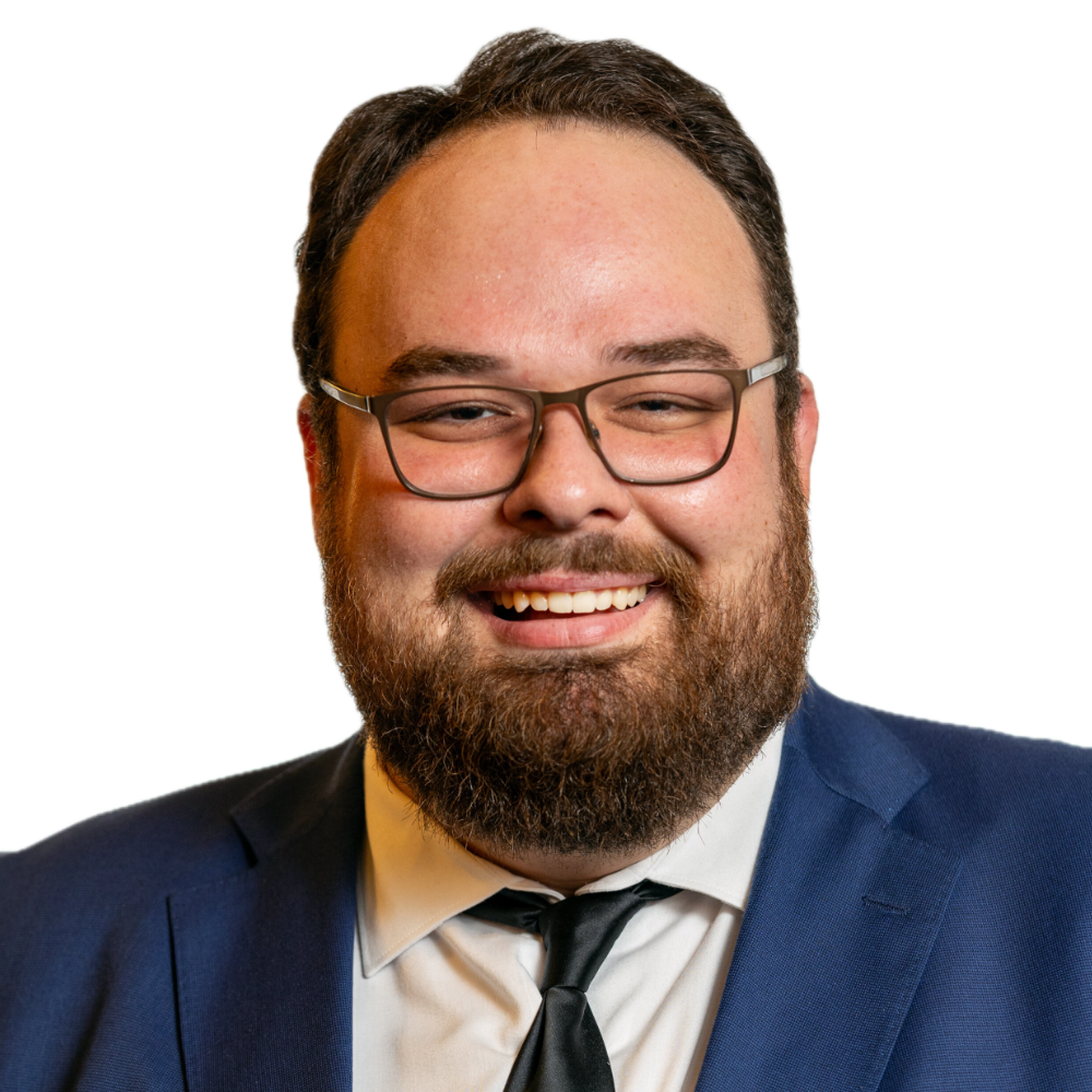 Ben Bond smiling headshot wearing a navy blue blazer, a white dress shirt, and a black tie