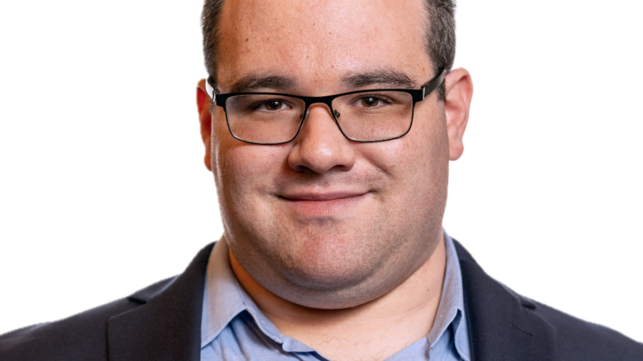Eric Ascher smiling headshot wearing a dark blue blazer and a light blue dress shirt