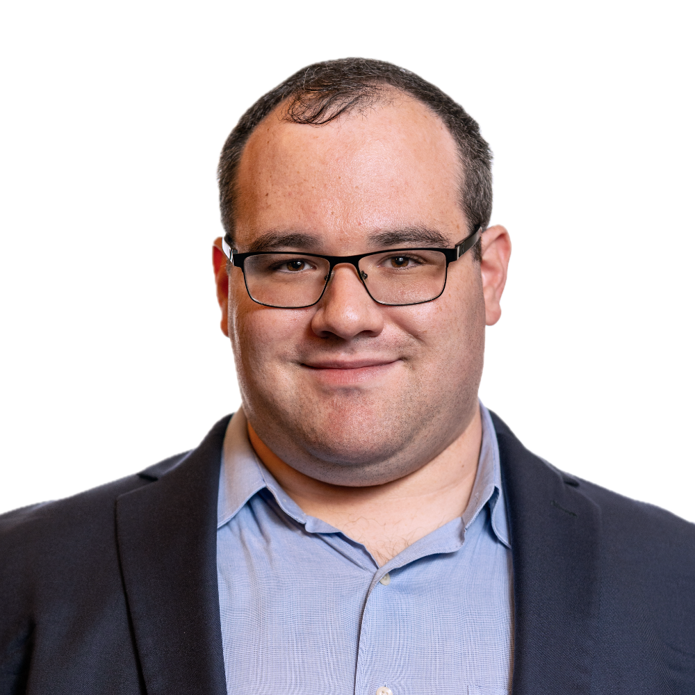 Eric Ascher smiling headshot wearing a dark blue blazer and a light blue dress shirt