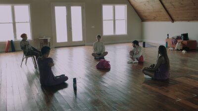 still from the short film POSSUM with the five characters in a large room seated in a circle