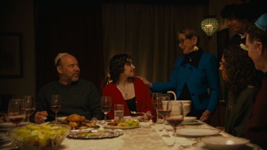 a still from Unholy with the cast seated around a dinner table having a conversation