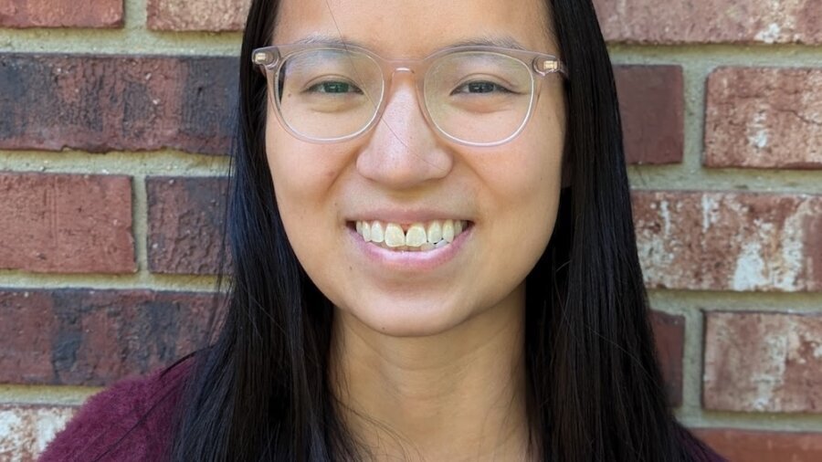 Olivia Hall smiling headshot in front of a brick wall