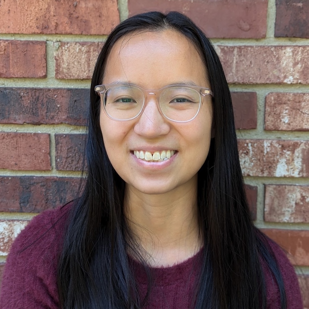Olivia Hall smiling headshot in front of a brick wall