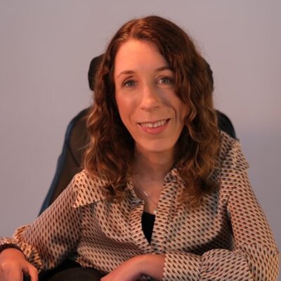 Natalie Lomske smiling seated in her power wheelchair