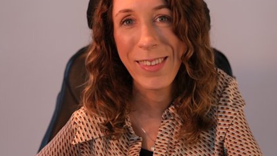 Natalie Lomske smiling seated in her power wheelchair
