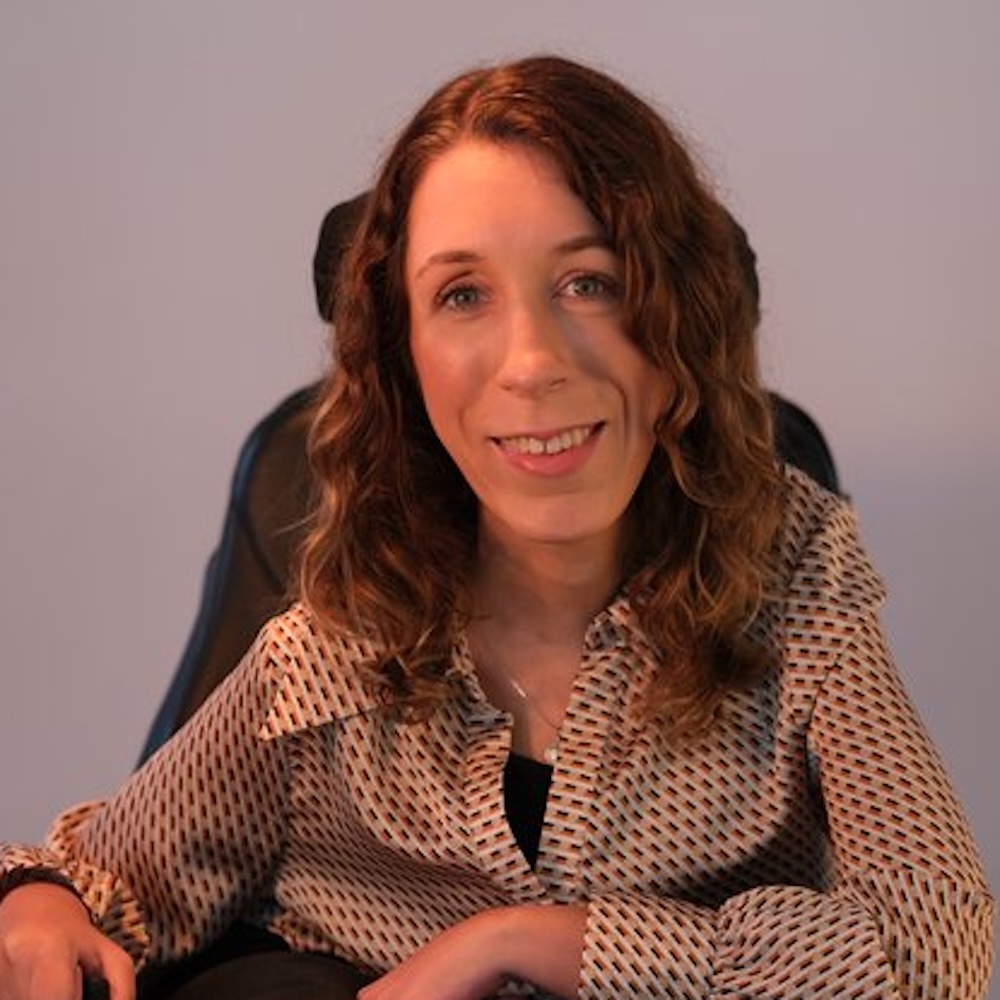 Natalie Lomske smiling seated in her power wheelchair