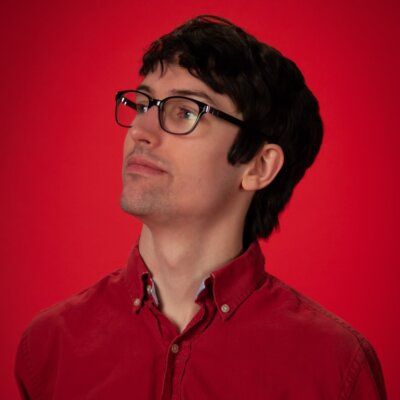 Sam Dunnewold headshot wearing glasses and a red shirt