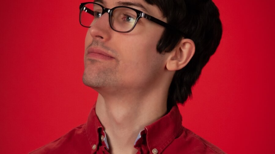 Sam Dunnewold headshot wearing glasses and a red shirt