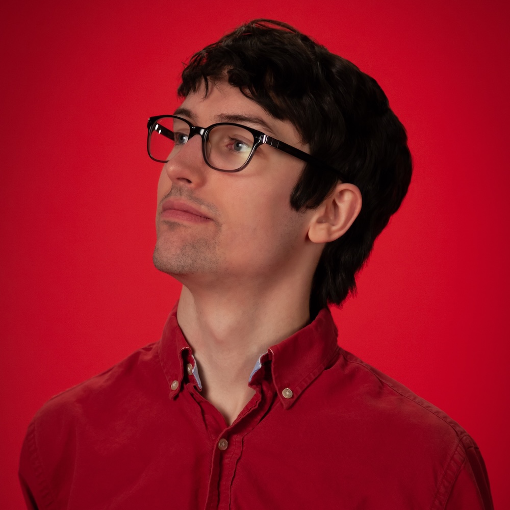 Sam Dunnewold headshot wearing glasses and a red shirt