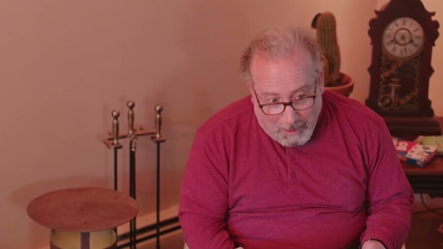 still from Nightmare with a man seated with swords in a stand and old clocks surrounding him